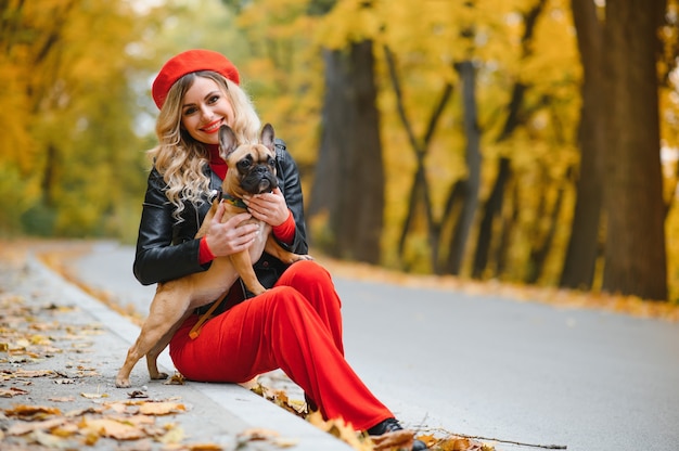 Mujer hermosa y feliz disfrutando en el parque caminando con su adorable bulldog francés.