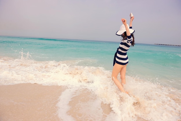 Mujer hermosa feliz disfrutando de las vacaciones de verano en la playa