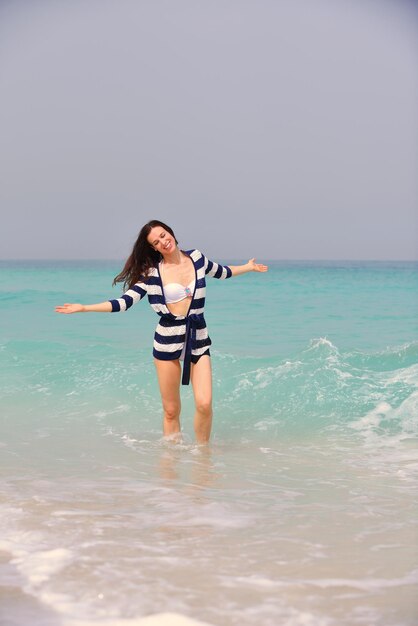 Mujer hermosa feliz disfrutando de las vacaciones de verano en la playa