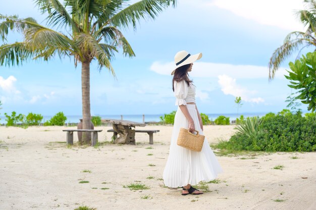 Una mujer hermosa feliz en vestido blanco disfrutando y relajándose en la playa