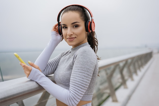 Mujer hermosa fitness en ropa deportiva escuchando música en auriculares.