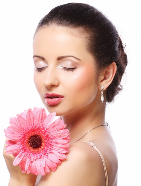 Mujer hermosa con la flor rosada aislada en blanco