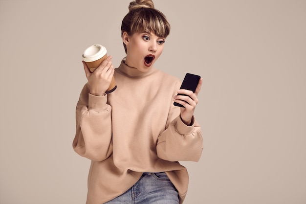 Mujer hermosa glamour rubia hipster con taza de café y teléfono