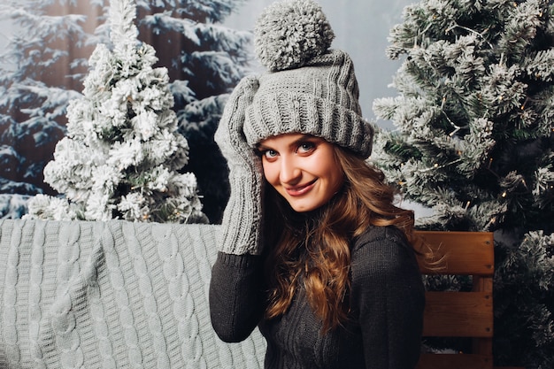 Mujer hermosa en gorro de punto gris y guantes.