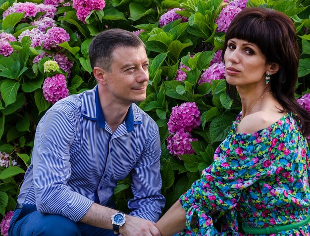 Mujer hermosa con un hombre entre flores en el parque.