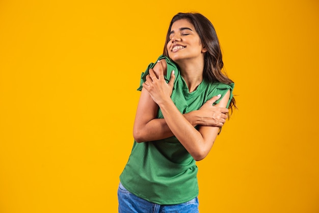 Mujer hermosa joven abrazándose a sí mismo feliz y positivo, sonriendo confiado. amor propio y cuidado personal