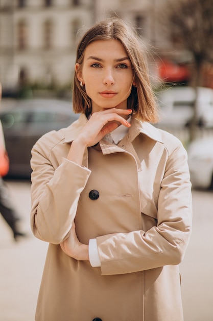 Mujer hermosa joven con abrigo caminando en la ciudad