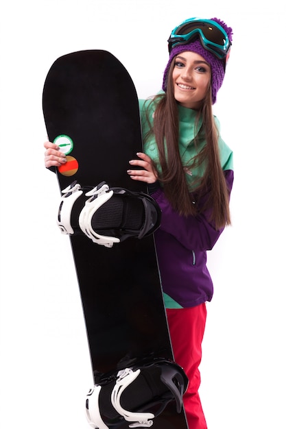 Mujer hermosa joven en abrigo de esquí púrpura y gafas de sostener snowboard