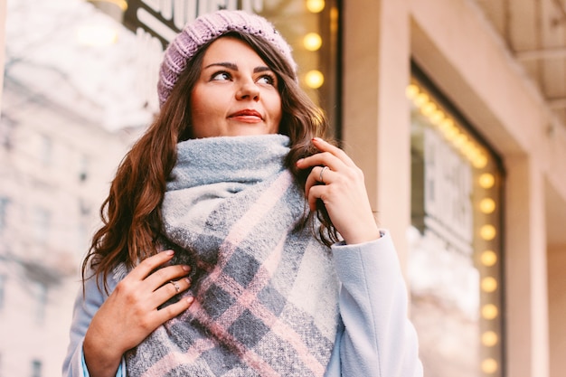 Mujer hermosa joven en abrigo y sombrero a finales de otoño o invierno o