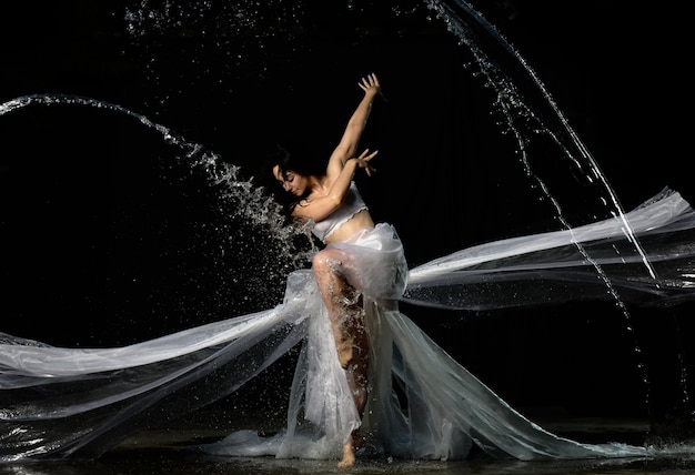 Mujer hermosa joven de apariencia caucásica con el pelo largo baila en gotas de agua