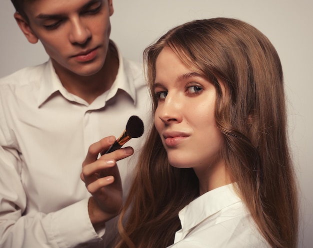 Mujer hermosa joven aplicar maquillaje por artista de maquillaje