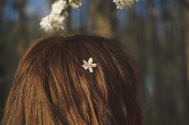 Mujer hermosa joven entre árboles en flor vista posterior concepto de primavera