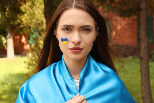 Mujer hermosa joven con bandera ucraniana en el parque