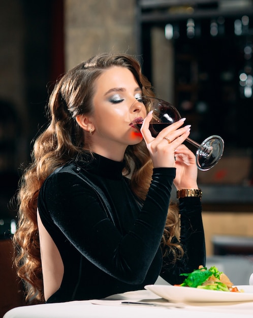 Mujer hermosa joven bebiendo vino en un restaurante.