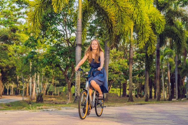 Mujer hermosa joven en bicicleta en un parque. Gente activa. Al aire libre