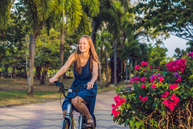 Mujer hermosa joven en bicicleta en un parque. Gente activa. Exterior