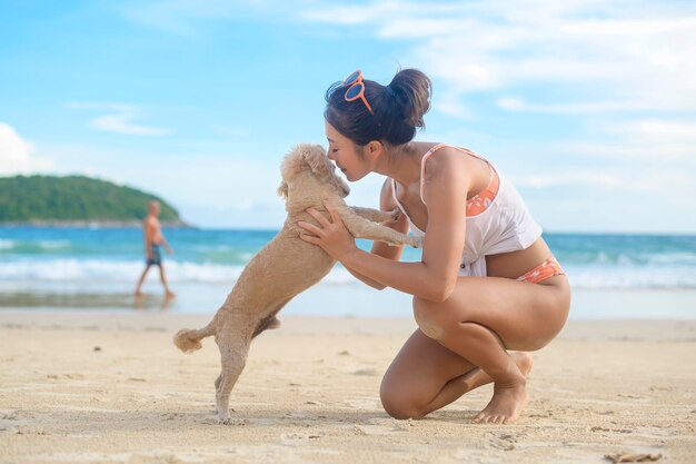 Mujer hermosa joven en Bikini con su perro disfrutando y relajándose en la playa