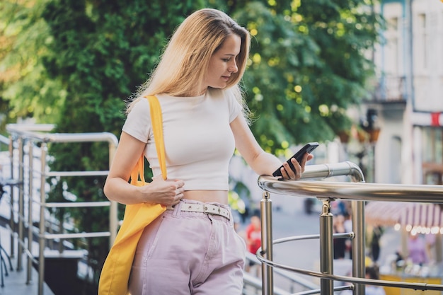 Mujer hermosa joven con bolsa ecológica de lino en el fondo de la ciudad