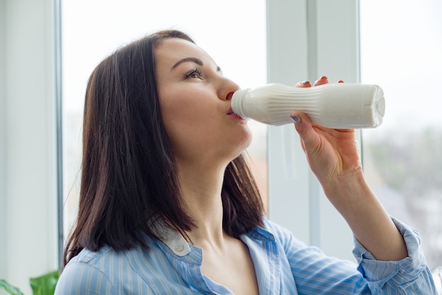 Mujer hermosa joven con botella de leche, yogur, productos lácteos.