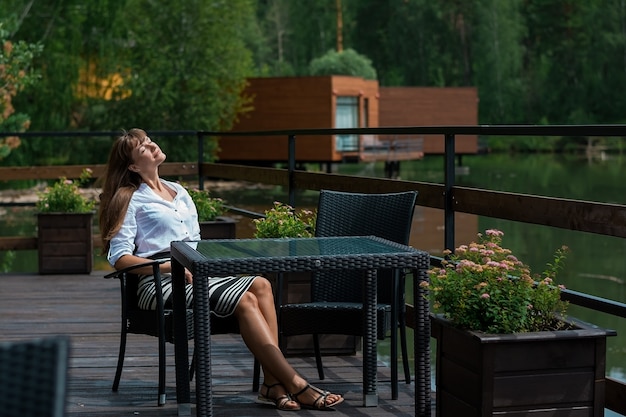 Mujer hermosa joven en un café de verano junto al río