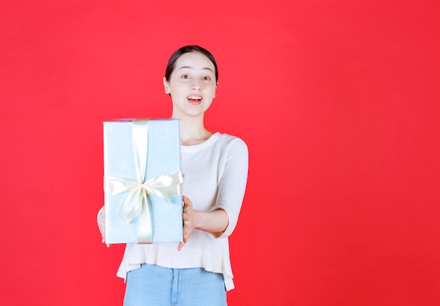 Mujer hermosa joven con caja de regalo y mirando a la cámara