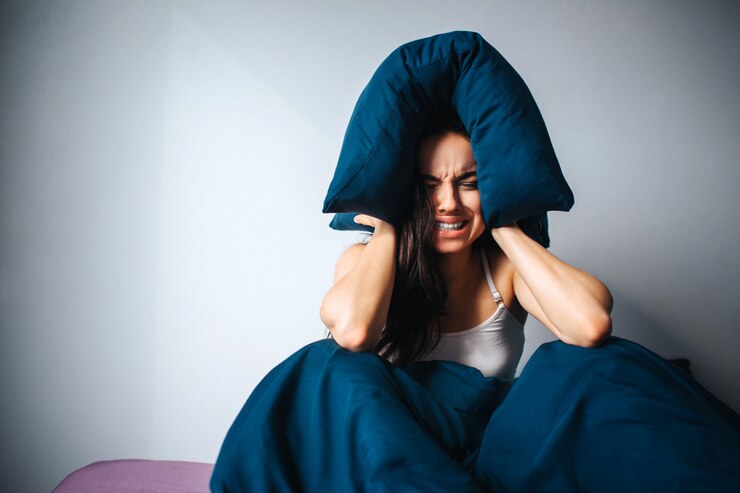 Foto mujer hermosa joven en cama de la mañana en casa. persona de sexo femenino irritada sufre de ruido. sostenga la almohada alrededor de la cabeza y listo para llorar. solo en la habitación deprimido.
