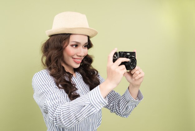 Mujer hermosa joven con cámara sobre fondo verde