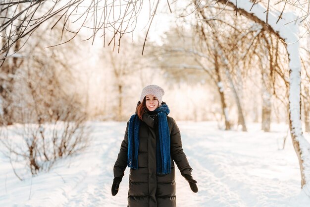 Una mujer hermosa joven camina por un sendero en un bosque de invierno cubierto de nieve