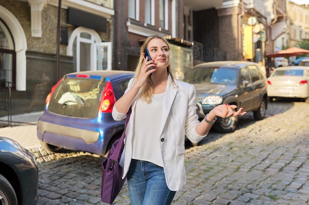 Mujer hermosa joven caminando por la calle de la ciudad hablando por teléfono móvil