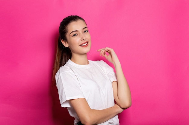 Mujer hermosa joven en una camiseta blanca se encuentra sobre un fondo rosa. Bosquejo.