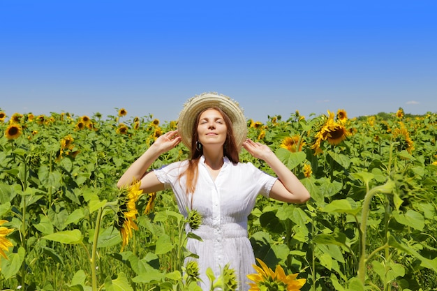 Mujer hermosa joven en campo floreciente del girasol en verano