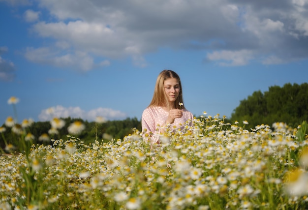 Mujer hermosa joven en el campo con margaritas blancas