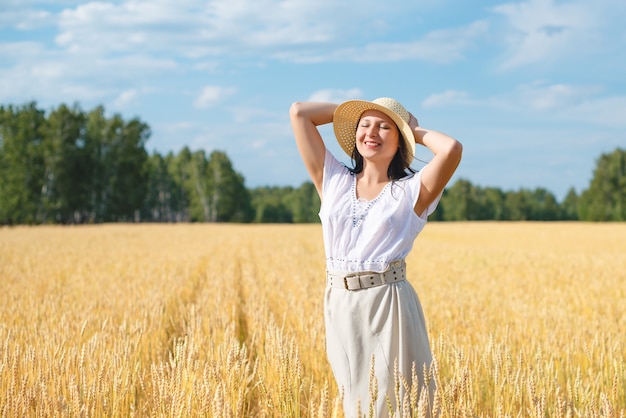 Mujer hermosa joven en campo de trigo dorado