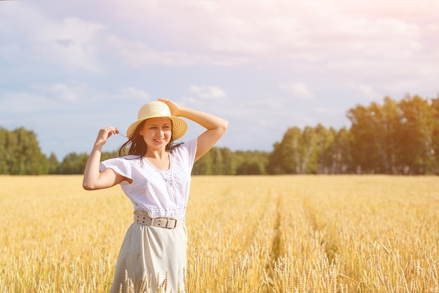 Mujer hermosa joven en campo de trigo dorado.