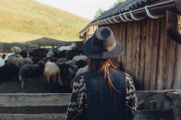 Una mujer hermosa joven cerca de un corral con cabras