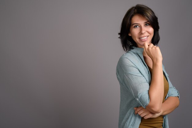 Mujer hermosa joven contra fondo gris