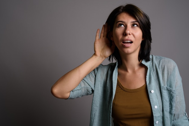 Mujer hermosa joven contra fondo gris