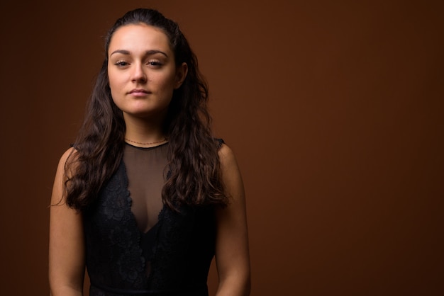 Mujer hermosa joven contra la pared marrón