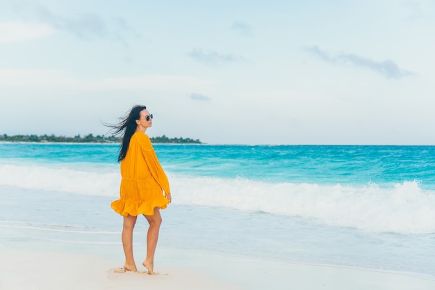 Mujer hermosa joven en la costa tropical en puesta de sol.