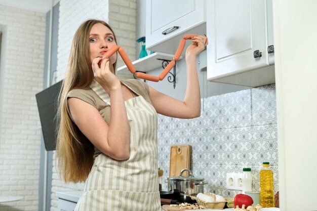 Mujer hermosa joven en delantal cocinar en casa en la cocina