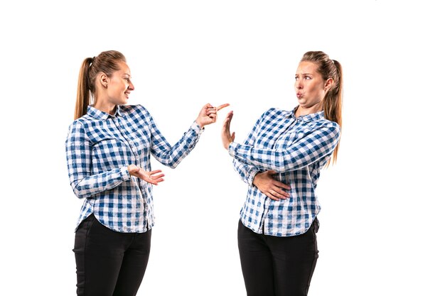 Foto mujer hermosa joven discutiendo consigo misma sobre fondo blanco de estudio.