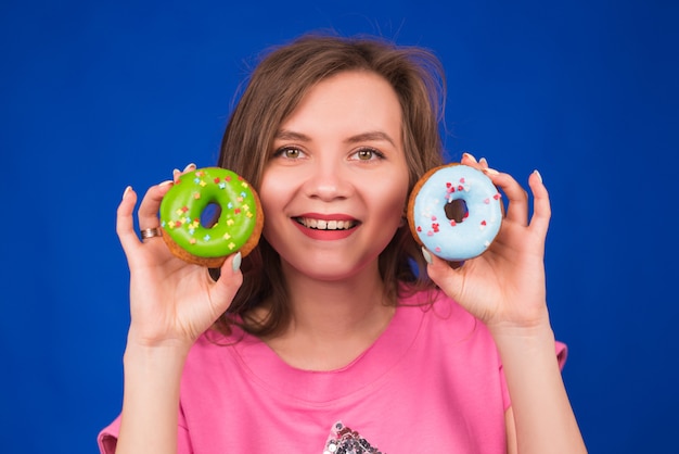 Mujer hermosa joven con donut en azul