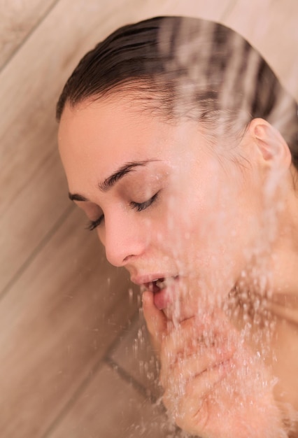 Mujer hermosa joven bajo la ducha en el baño.