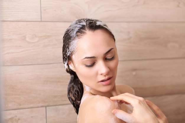 Mujer hermosa joven bajo la ducha en el baño.