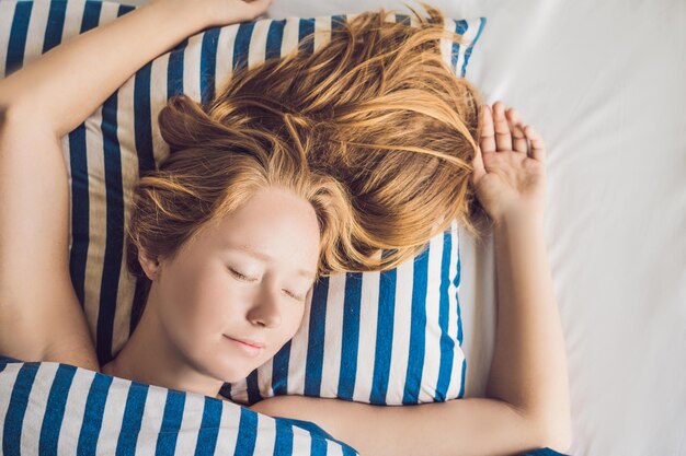 Mujer hermosa joven durmiendo en su cama y relajándose por la mañana.