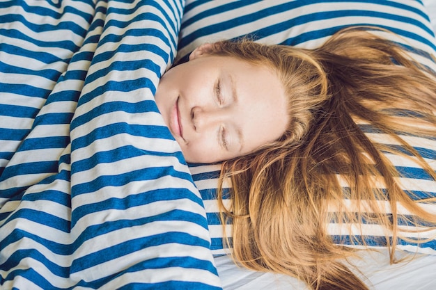 Mujer hermosa joven durmiendo en su cama y relajándose por la mañana.