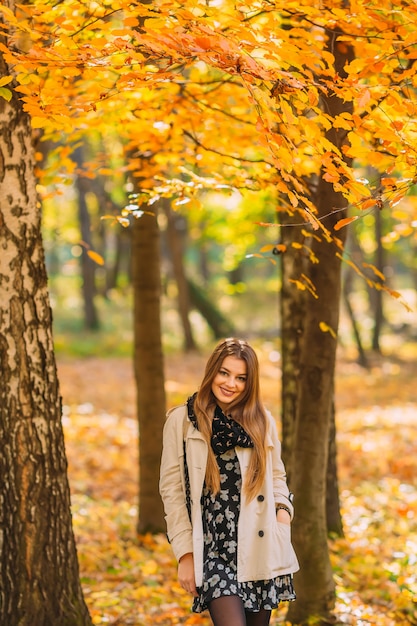 Mujer hermosa joven en un elegante abrigo de otoño caminando en el parque en un día soleado. . Otoño mujer divirtiéndose en el parque y sonriendo. Retrato de mujer joven en color de otoño.