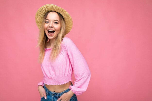 Mujer hermosa joven en elegante blusa de verano rosa y moda sombrero de paja espectáculos femeninos positivos