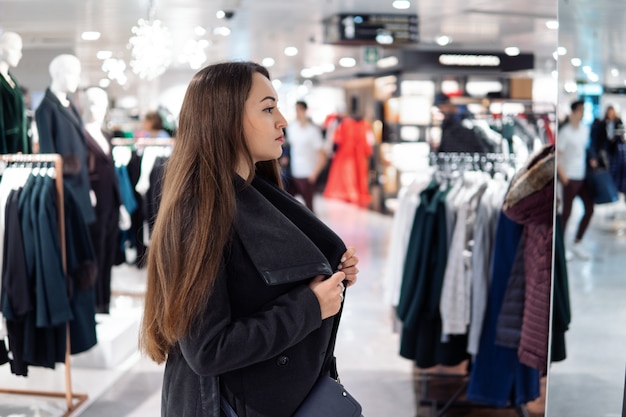 Mujer hermosa joven encontrando ropa nueva en una tienda supermercado