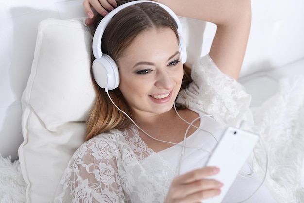 Mujer hermosa joven escuchando música en el sofá en casa